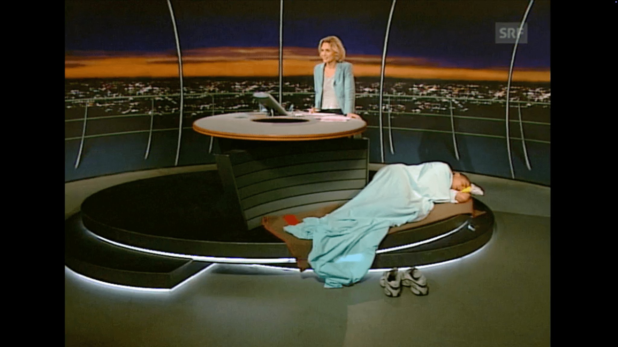 San Keller, San Keller schläft an Ihrem Arbeitsplatz (San Keller sleeps at your workplace). Performance live at Swiss Broadcasting Corporation SRF, 10vor10, 14.7.2000. Courtesy the artist.