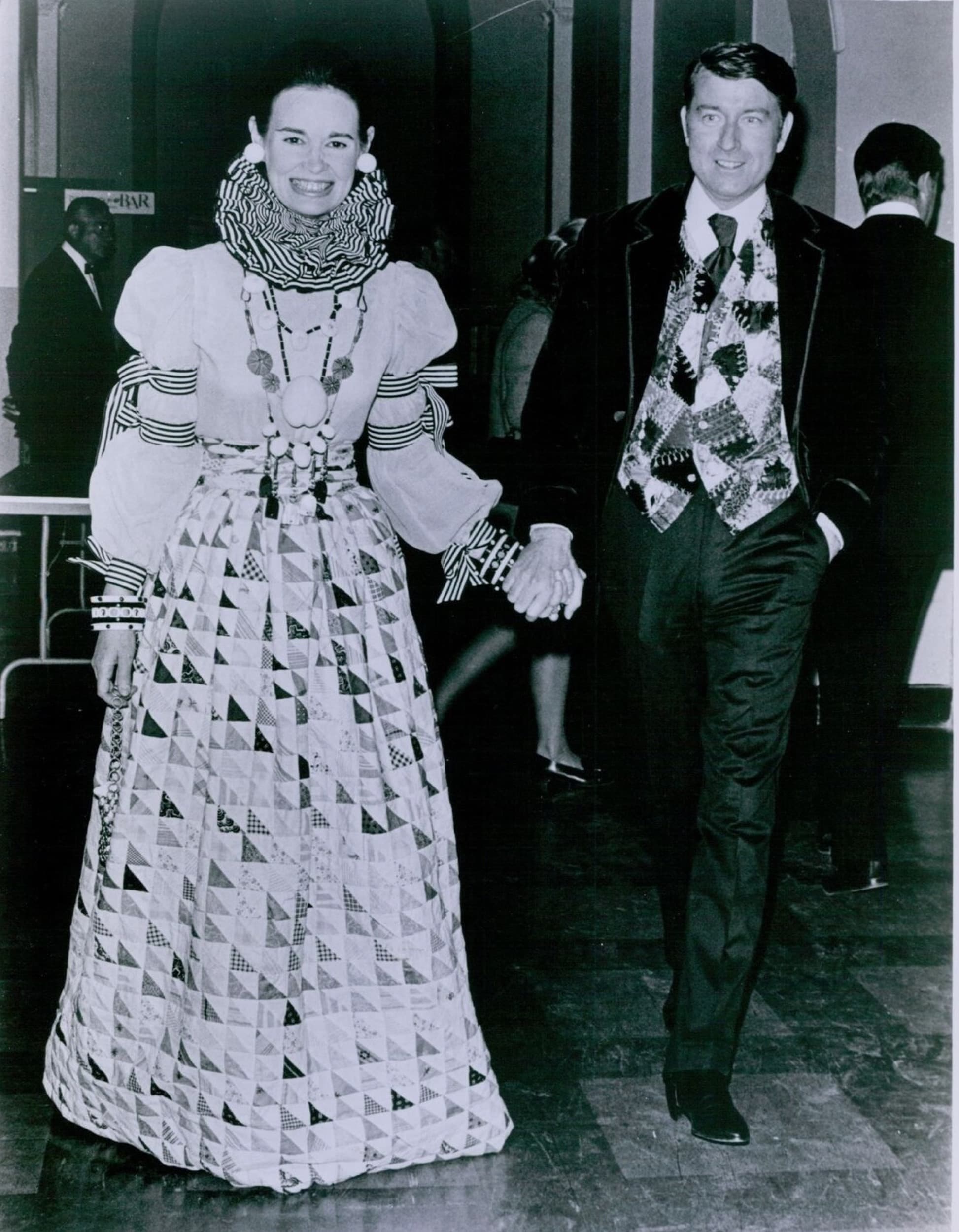 Gloria Vanderbilt Cooper and her husband, Wyatt Emory Cooper, in 1970. Gloria is wearing an outfit made from an antique patchwork quilt by the designer Adolfo in 1967 (now in the V&A Museum) and her husband is wearing a waistcoat also made from an antique quilt. Public domain, via Wikimedia Commons.
